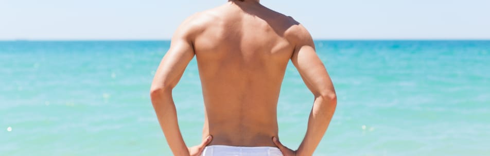 back of fit man facing the ocean - liposuction orlando