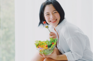 Asian young beautiful woman eating salad with happy mood smile