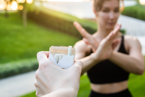 young woman refuses cigarettes shows with hands a stop symbol