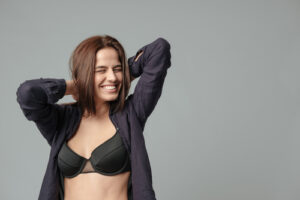 Smiling woman in bra posing over gray background